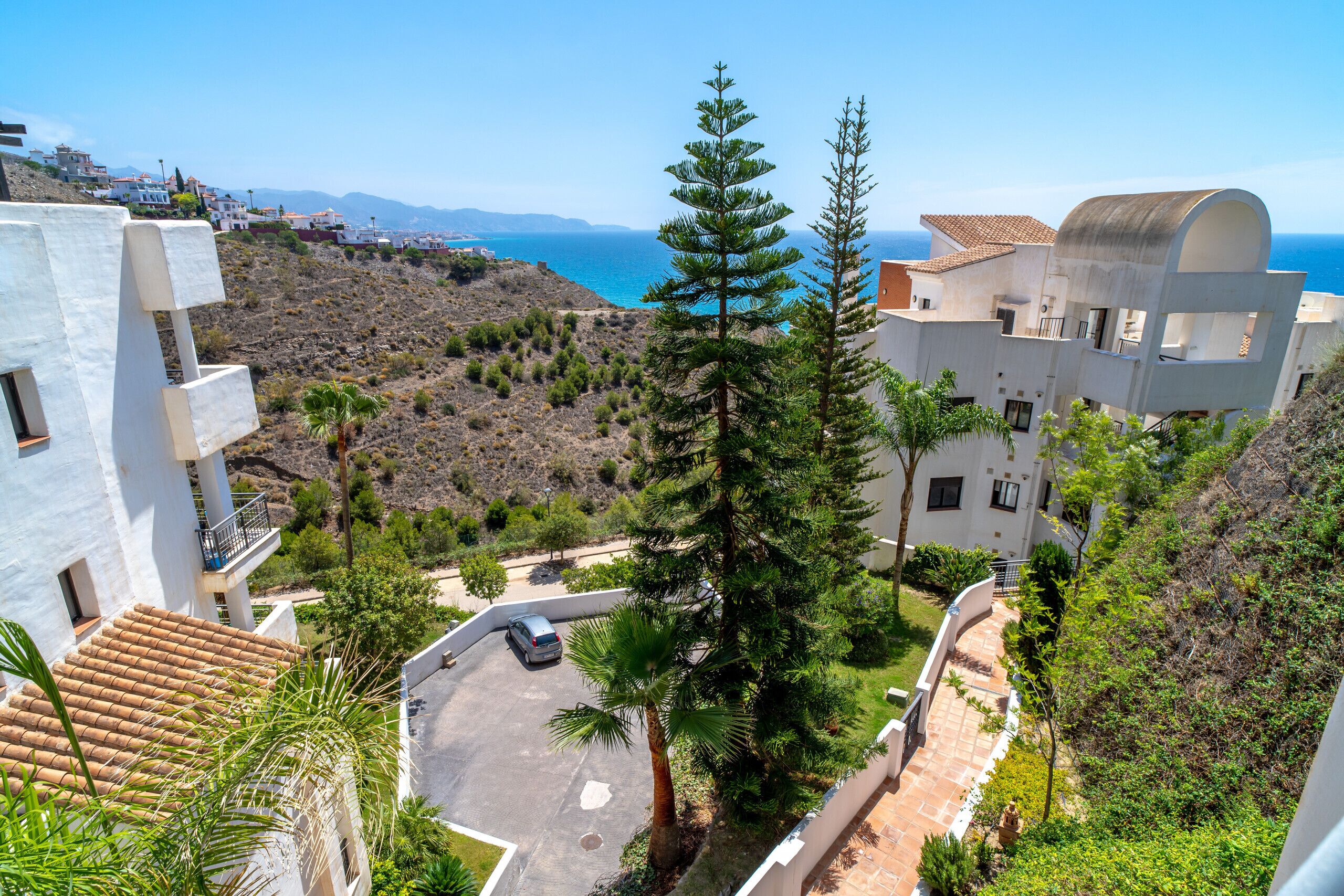 A coastal residential area with modern architecture, including a curved building and a white building with a balcony.