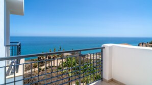 Un balcon avec vue sur l’océan et un ciel d’un bleu limpide.