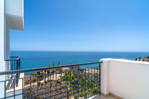 A balcony with a view of the ocean and a clear blue sky.