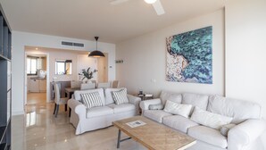Un salon moderne avec un canapé blanc, une table basse en verre et un ventilateur de plafond.