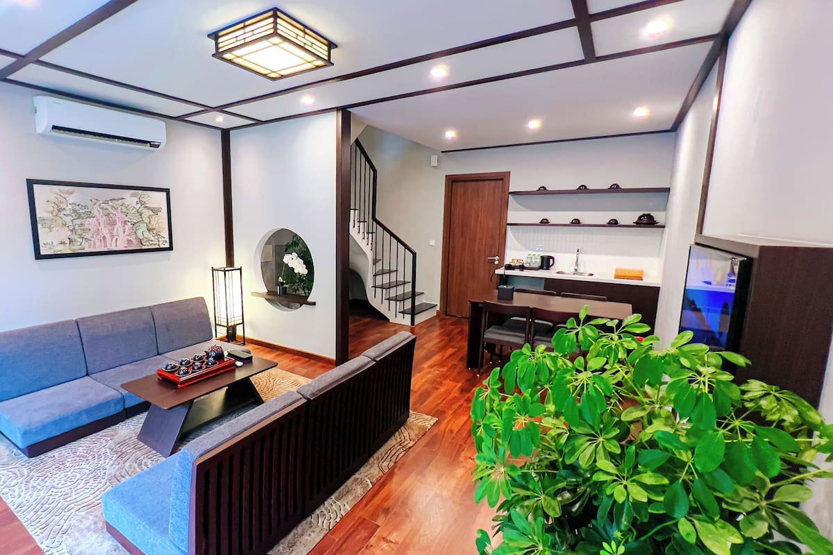 Un espacio moderno de estar con sofá, mesa de centro y una escalera que lleva a una zona de cocina.