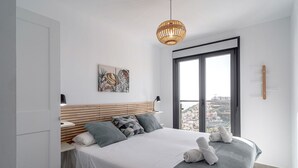Ein modernes Schlafzimmer mit einem großen Bett, Blick auf die Stadt durch das Fenster und einer hängenden Leuchte.