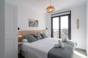 Ein modernes Schlafzimmer mit einem großen Bett, Blick auf die Stadt durch das Fenster und einer hängenden Leuchte.