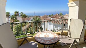 A balcony with a view of the sea, palm trees, and buildings. - Senorio de Capistrano by Casasol (Nerja)