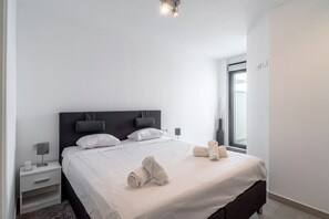 Ein modernes Hotelzimmer mit einem großen Bett, Nachttischen und einem Fenster, das für natürliches Licht sorgt.