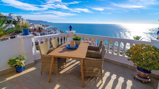 A terrace with a table and chairs, potted plants, and a view of the sea. - Vistas del Mar by Casasol (Nerja)