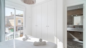 Ein Hotelzimmer mit Bett, großem Fenster, Kleiderschrank und Badezimmer mit Spiegel und Waschbecken.