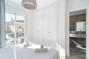 A hotel room with a bed, a large window, a wardrobe, and a bathroom with a mirror and sink. - Villa Andalucía Esplendor by Casasol (Nerja)
