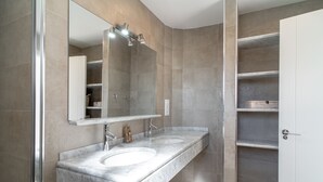 Ein modernes Badezimmer mit zwei Waschbecken, einem großen Spiegel und einer Duschkabine.