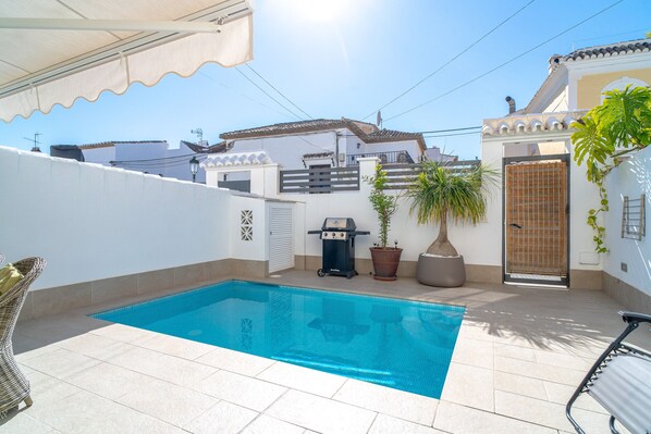 A swimming pool with a tiled deck, a barbecue grill, and potted plants. - Villa Andalucía Esplendor by Casasol (Nerja)
