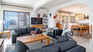Un soggiorno moderno con divano, tavolino e televisore. C’è anche un’area pranzo con tavolo e sedie.