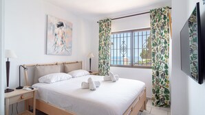 Camera da letto con un letto, comodini, una lampada, un quadro e tende.