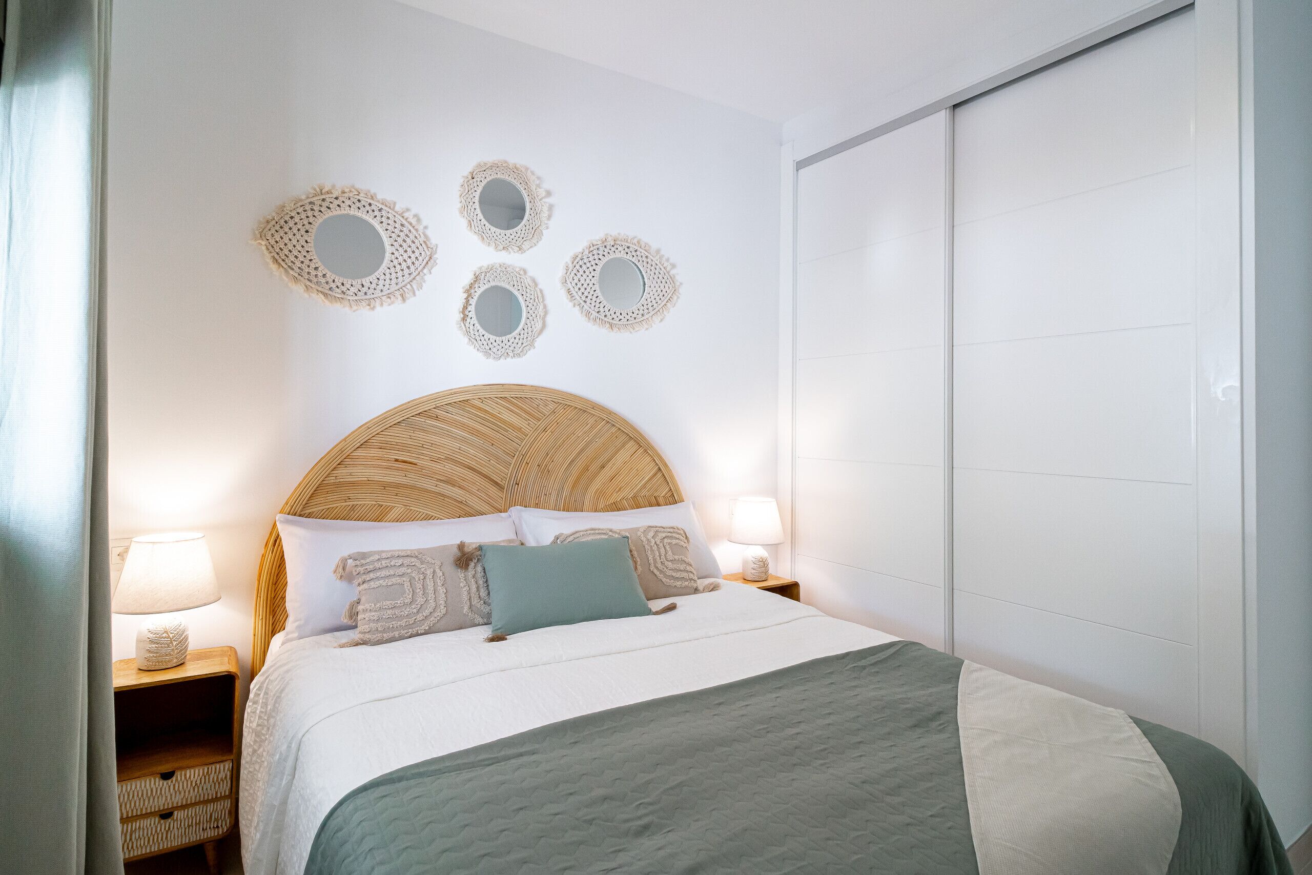 Un dormitorio ordenado con una cama grande, dos mesitas de noche con lámparas y un armario.