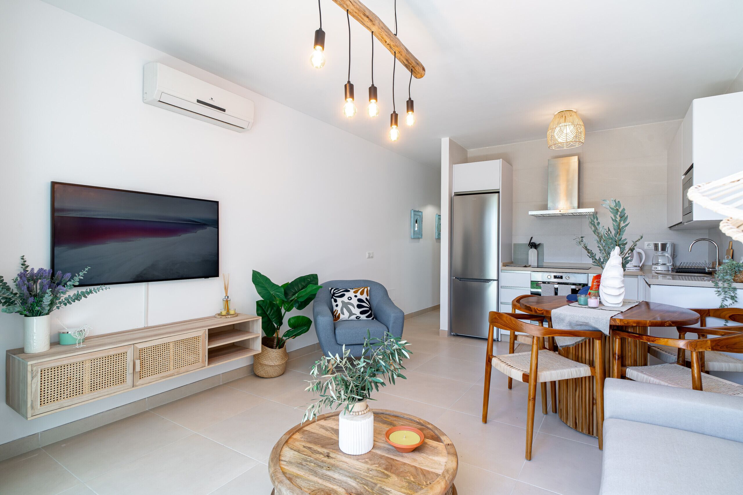 Una sala de estar moderna con un televisor de pantalla plana, muebles de madera y un comedor con mesa y sillas.