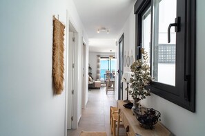 Ein Flur mit Essbereich, einer Pflanze und einem Fenster mit Jalousien.