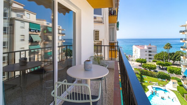 A balcony with a table and chairs, overlooking a swimming pool and a view of the sea. - Albaida Seaview by Casasol (Nerja)