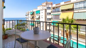 A balcony with a table and chairs, overlooking a pool and buildings with balconies. - Albaida Seaview by Casasol (Nerja)