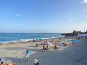 Ein Strand mit Menschen, die sich sonnen und am Ufer entlanggehen.