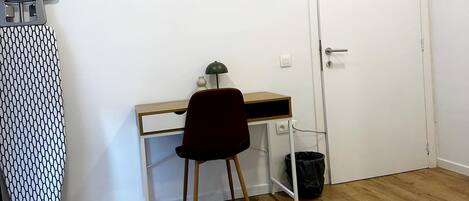 Une chambre à coucher avec un lit, un bureau, une chaise, une porte et une planche à repasser.