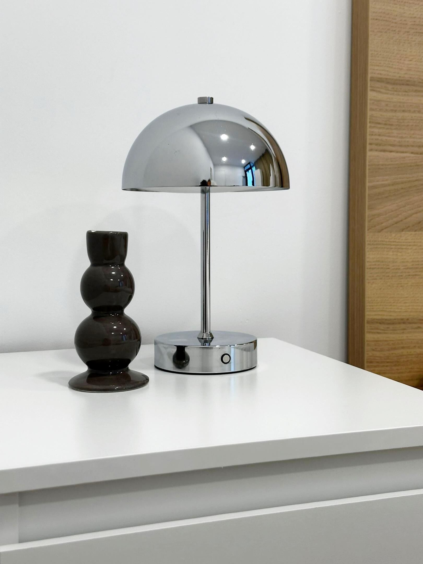 A modern lamp with a metallic finish on a white surface.