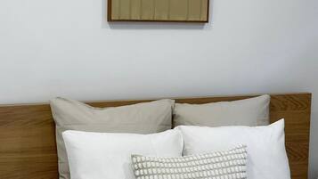 Una cama con cabecera de madera, dos almohadas y una obra de arte colgada en la pared.