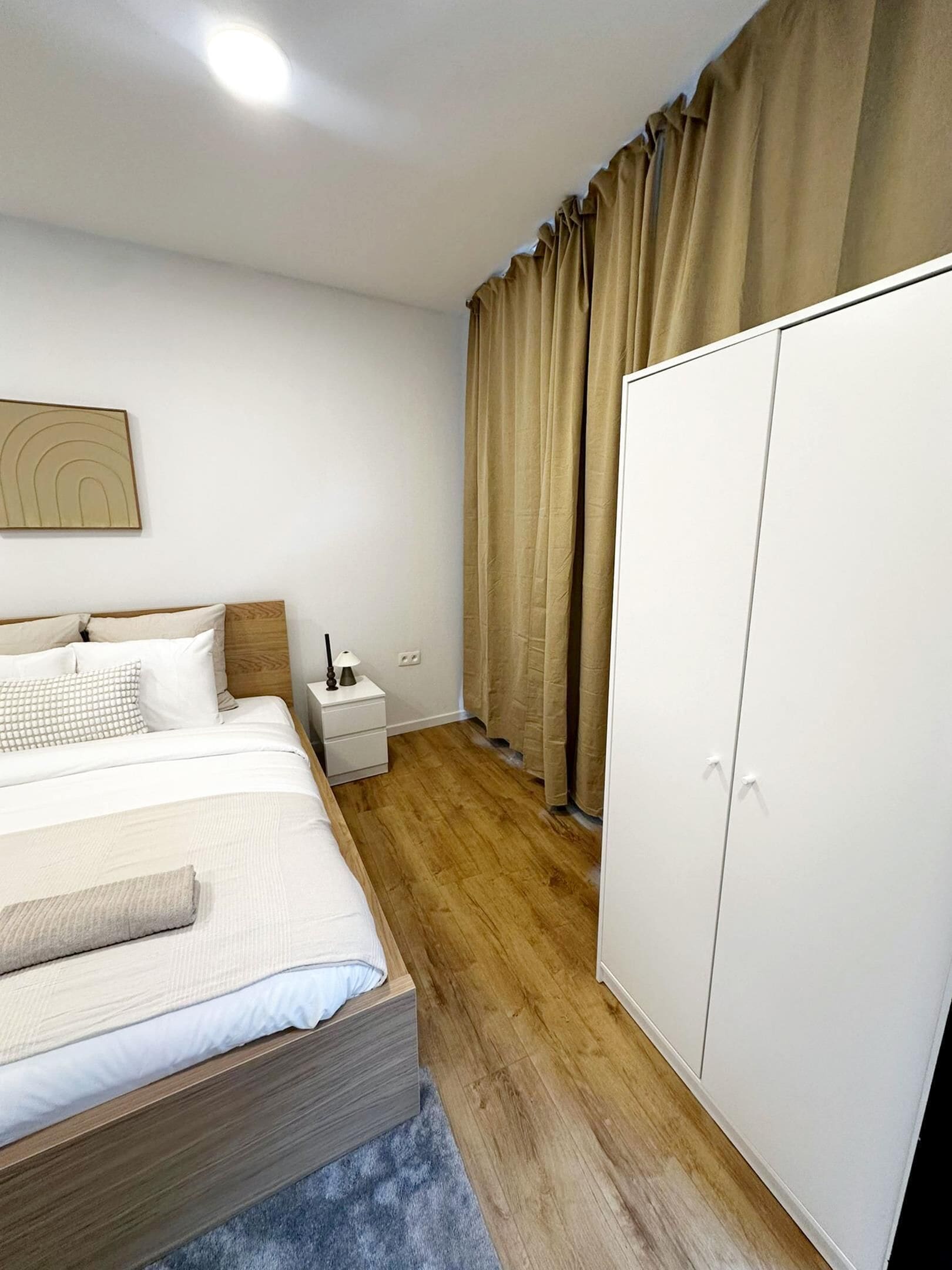 Ein Schlafzimmer mit Bett, Nachttisch, Kleiderschrank und einem Bild an der Wand.