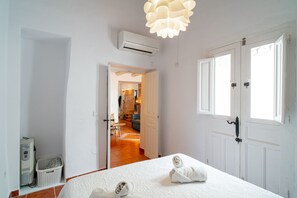 Ein Hotelzimmer mit einem Bett, einer weißen Tür, einer Klimaanlage und einem Wäschekorb.