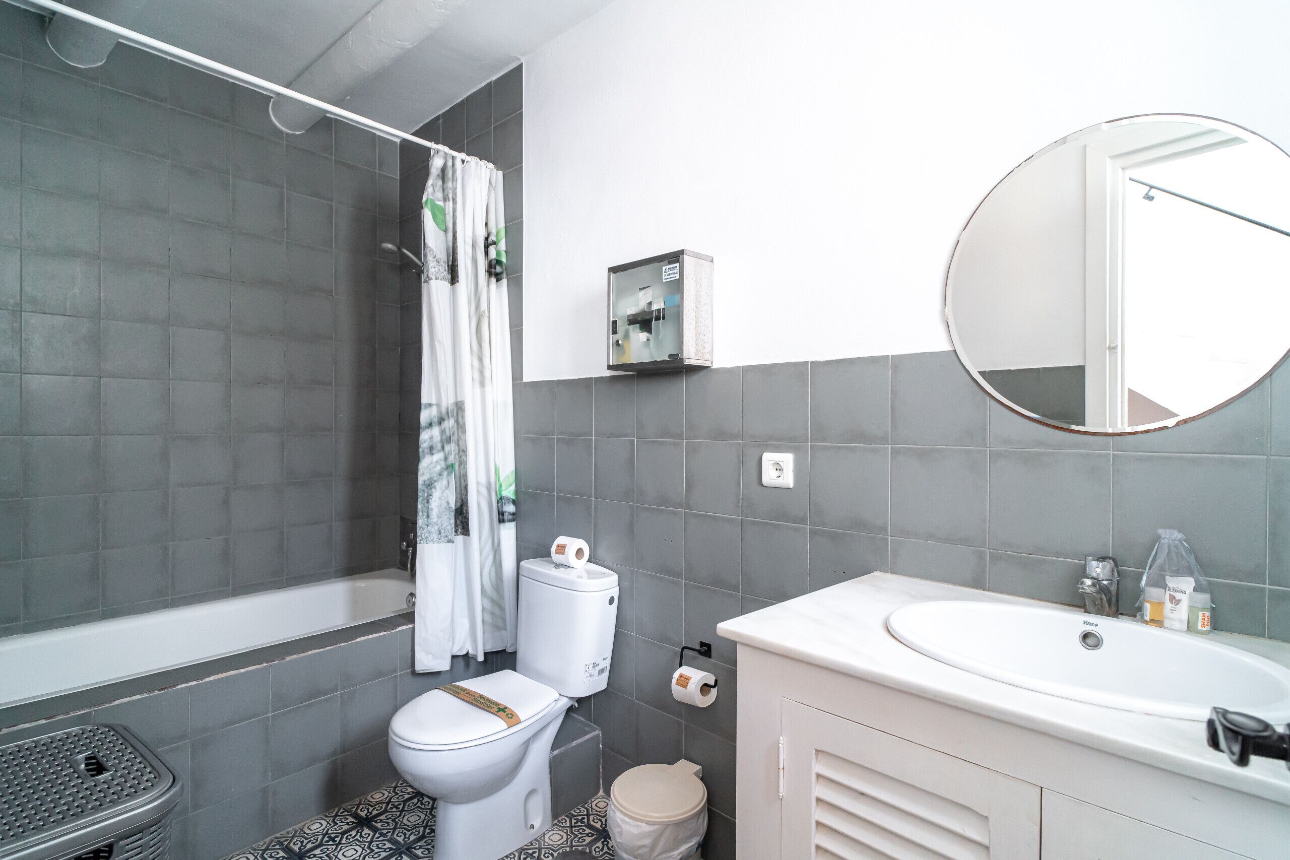 Et badeværelse med badekar, toilet, håndvask og et spejl.
