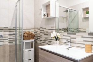 A modern bathroom with a glass shower enclosure, a white sink with a mirror, and a tiled backsplash. - Seasight Apartment by Wonderful Italy (Bari)