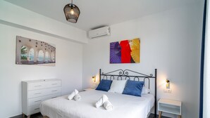 Un dormitorio moderno con una cama grande, un aparador blanco y un aire acondicionado de pared.