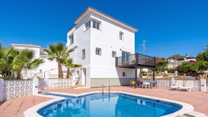 Un edificio blanco con piscina, balcón y mobiliario exterior.