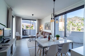 Ein modernes Wohnzimmer mit Essbereich, großen Fenstern und Blick ins Freie.
