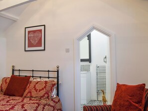 A bedroom with a bed, a chair, a framed picture, and a door leading to a bathroom. - 1 bedroom accommodation in Wadebridge (Wadebridge)