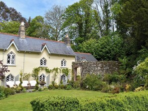 A large house with a stone wall, multiple chimneys, and a well-maintained garden. - 1 bedroom accommodation in Wadebridge (Wadebridge)