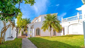 A white building with a paved pathway, palm trees, and a clear blue sky. - Villa Grande Luxe Private Pool (Nerja)