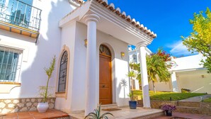 A white building with a wooden door, columns, and a tiled entrance. - Villa Grande Luxe Private Pool (Nerja)