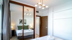 A hotel room with a bed, a mirror, a wooden door, and a ceiling light fixture. - Villa Grande Luxe Private Pool (Nerja)