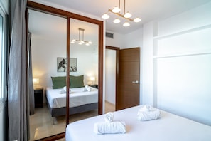 Ein Hotelzimmer mit Bett, Spiegel, Holztür und Deckenleuchte.