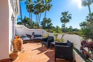 A patio with wicker furniture, a large terracotta pot, and a view of palm trees. - Casablanca Sunny Terrace by Casasol (Nerja)