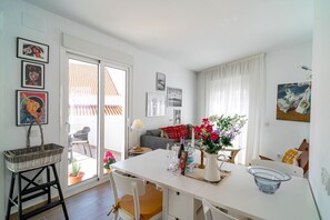 A bright living room with a white table, chairs, and a sofa. There are framed pictures on the walls and a basket on a stand. - Casa Alegre by Casasol (Nerja)