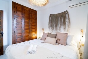 Ein Schlafzimmer mit großem Holzschrank, einem Bett mit aufgerollten weißen Handtüchern und einer Wandleuchte.