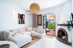 Ein modernes Wohnzimmer mit einem Ecksofa, einem Kamin und Blick auf die Terrasse.