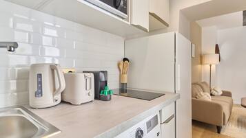 Et kompakt køkken med mikroovn, elkedel, brødrister og kaffemaskine.