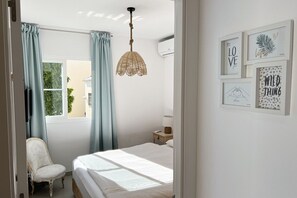 A bedroom with a bed, a chair, a hanging light fixture, and wall art. - Jardines de Burriana Deluxe by Casasol (Nerja)