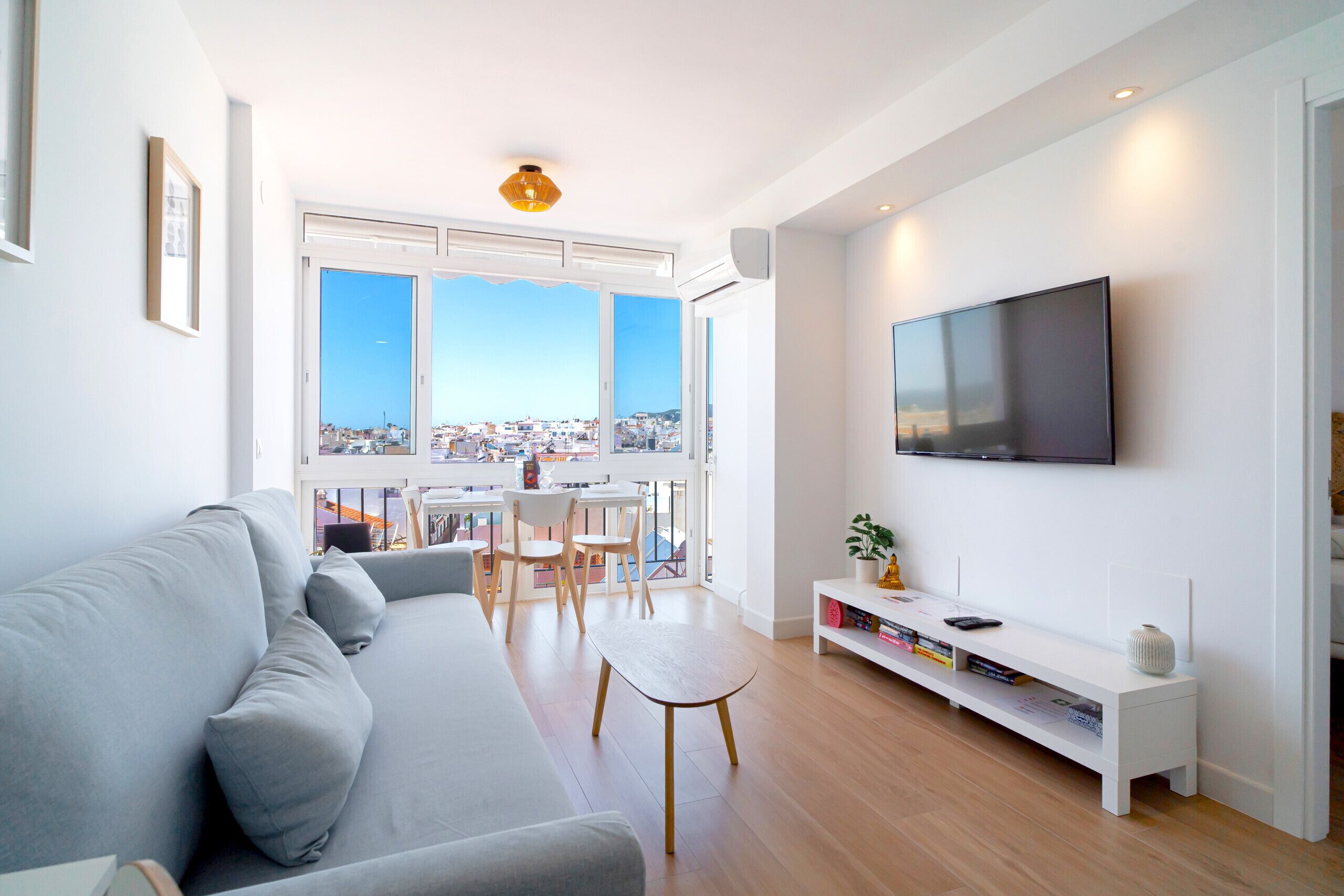 A modern living room with a grey sofa, wooden coffee table, and a TV mounted on the wall.