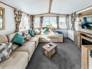 Ein modernes Wohnmobil-Interieur mit einer Eckcouch, einem Couchtisch und einem Fernseher.