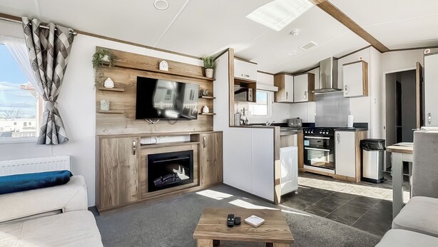 Un soggiorno moderno con camino, TV e cucina completa di fornello e forno.