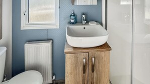 Un bagno con lavandino bianco, mobiletto in legno e vaso igienico bianco.