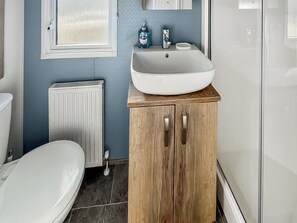 Ein Badezimmer mit Waschbecken, Holzschrank und Toilette, alles in Weiß.
