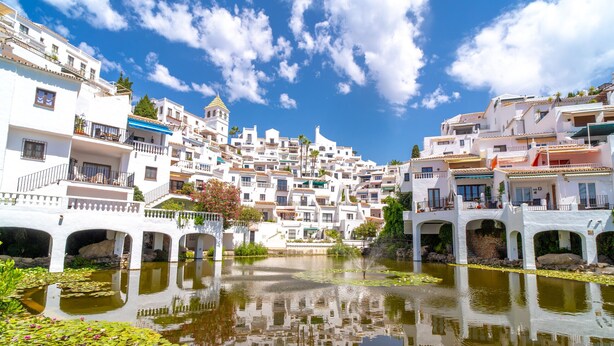 A coastal town with white buildings, a bridge, and a calm water body with lily pads. - Capistrano Playa 404 by Casasol (Nerja)